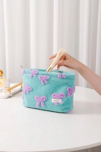 Detail of plush mint green cosmetic bag with purple bow and soft velvet texture