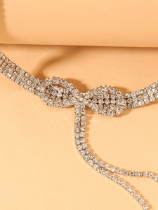 Macro detail of rhinestone bow and dangling tassel on silver chocker necklace