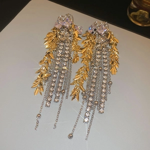 Detail of long fringe earrings with golden leaf accents and sparkling rhinestone chains