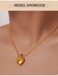 Golden heart pendant necklace on snake chain shown on a model neck for scale