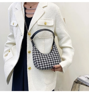 Detail of houndstooth crescent bag featuring premium gold chain and leather handle