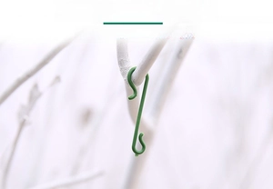 Close-up of green S-shaped plastic hooks for hanging Christmas ornaments on tree branches