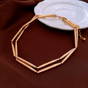 Detailed view of vintage golden tubular metal link necklace on brown fabric background