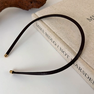 Detailed view of the dark leather headband with gold metal ends on a vintage book