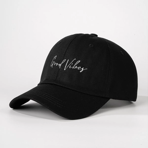 Detail of Good Vibes white embroidery on a premium black cotton baseball cap surface