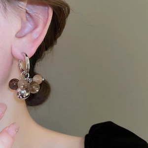 Macro side view of silver earrings with brown resin beads and metallic hoops on model