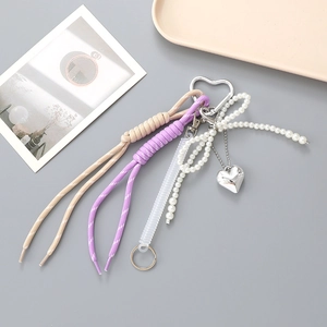 Gros plan de porte-clés tissés violets et beige avec nœud en perles et pendentif cœur