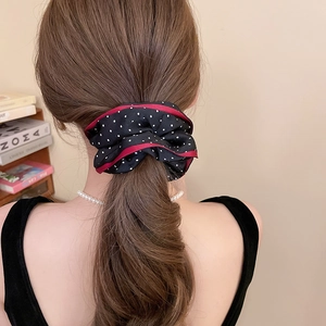 Detail of a large polka dot pleated scrunchie with red trim in a vintage elegant style