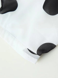 Nahaufnahme von weißem Chiffonstoff mit großen schwarzen Punkten und feinen Nähten