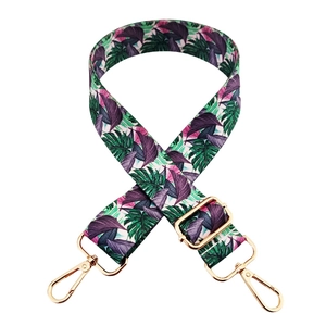 Detail of adjustable wide shoulder strap with vibrant tropical leaf patterns and gold hooks