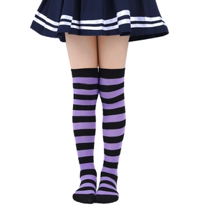 Detail view of purple and black striped over-knee socks worn with a pleated skirt