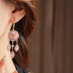 Close-up of vintage gold earrings featuring pink rhombus zircon tassels and crystal stones