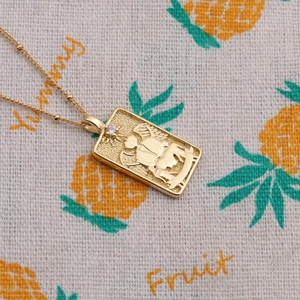 Détail du collier pendentif dieu du soleil plaqué or avec pierre sur fond en tissu