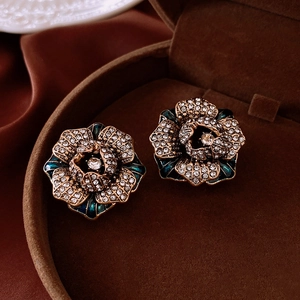 Macro shot of vintage green enamel flower earrings with crystals in a brown velvet box