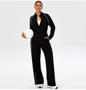Detail of black sporty jacket and trousers with white side piping on studio model