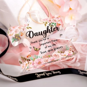 Macro view of puzzle-shaped acrylic plaque with pink floral prints and daughter poem
