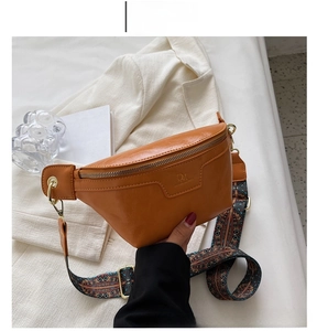 Detail of mustard yellow crossbody bag with vintage woven strap and embossed logo