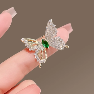 Golden butterfly brooch with sparkling crystals and a marquise-cut green gemstone