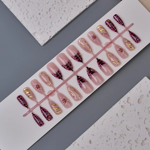 Detail of pink Y2K press-on nails with crocodile texture and golden embossed floral patterns