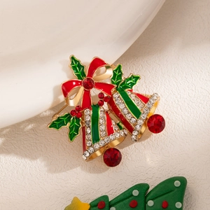 Detailed macro view of Christmas bell brooch with red bow and green enamel leaves
