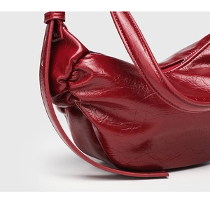 Detailed macro view of dark red soft leather texture and sewing on the crescent shoulder bag