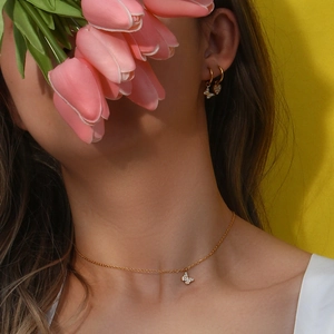 Close-up of a lady wearing a 18K gold butterfly necklace and matching zircon earrings