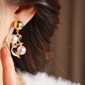 Gros plan de boucles d'oreilles dorées avec perles blanches et roses et diamants