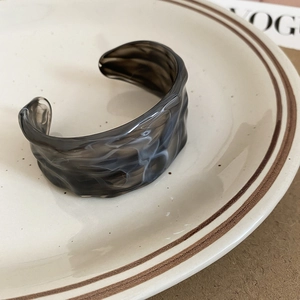 Macro view of wave-textured acrylic cuff bracelet with smoky grey marble pattern