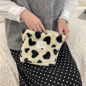 Detail of plush black and white heart pattern makeup bag with woven brand label