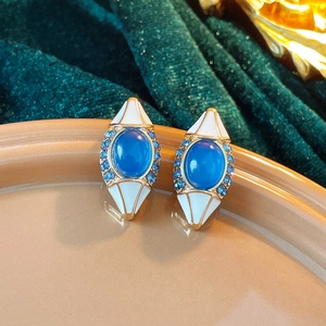 Gros plan détaillé de boucles d'oreilles vintage dorées avec pierres bleues et émail blanc