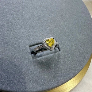 Elegant silver ring with a 6mm heart-shaped yellow diamond and halo setting on a gray stand