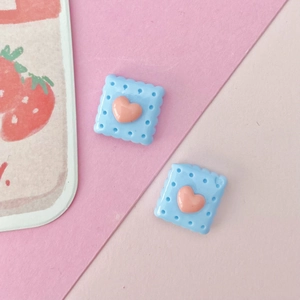 Macro detail of blue resin biscuit charms with pink hearts for DIY craft projects