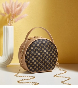 Détail d'un sac à main rond style vintage avec imprimé floral et bandoulière dorée