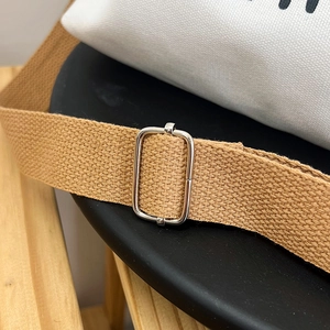 Close-up of adjustable silver metal buckle and durable khaki canvas shoulder strap