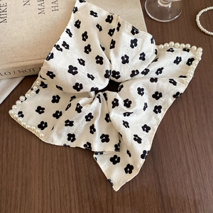 Close-up of white floral silk scrunchie with elegant pearl edge on dark wood