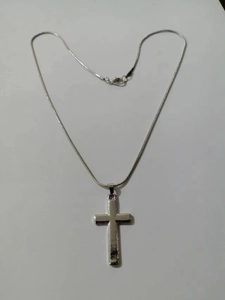 Detail of silver snake chain with polished cross pendant and secure lobster clasp closure
