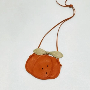 Close-up of orange fruit-shaped leather kids bag with detailed stitching and texture