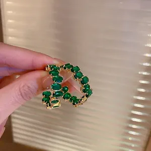 Eleganti cerchi a C dorati con pietre ovali verde smeraldo in uno stile vintage di lusso