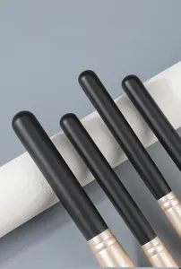 Detail of matte black wood handles and gold ferrules on professional makeup brushes