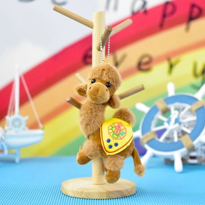 Detailed view of a cute brown camel plush keychain hanging on a wooden stand.