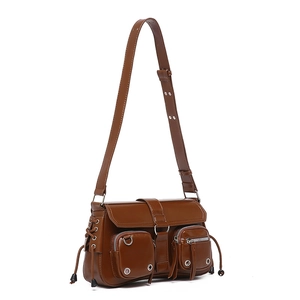 Detail of caramel brown leather shoulder bag with buckle straps and utility zipper pockets