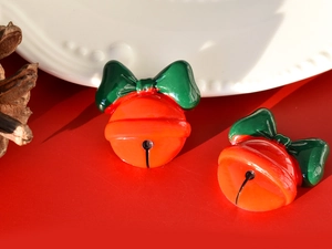 Close-up of two red resin Christmas bells with green bows for DIY crafts and decor
