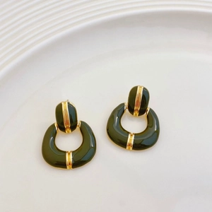 Detail of vintage French gold-plated earrings with green enamel and geometric horseshoe design