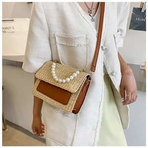 Close-up of straw woven bag with pearl handle and brown leather trim detailing