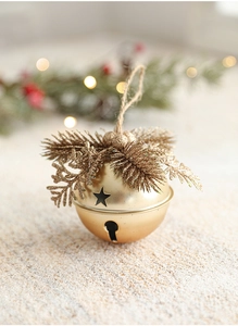 Macro view of a gold Christmas bell with pine needles, star cutouts and hemp rope hanging