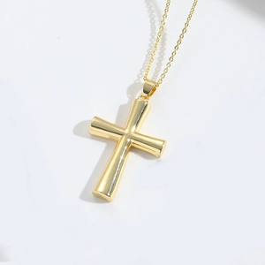Detail of polished gold cross pendant with sleek 3D curves on minimalist chain