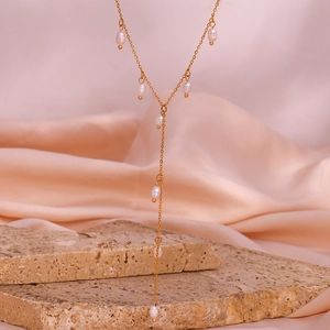 Détail macro d'un collier en Y doré avec d'élégantes perles d'eau douce sur une pierre