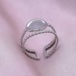 Macro view of adjustable silver steel ring with beaded dual-layer band on silk