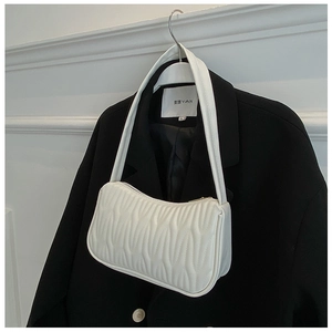 Detail of white wave embossed leather texture on shoulder bag over a black blazer