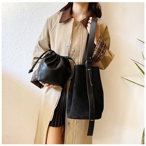 Detail of black suede bucket bag and leather drawstring pouch on a fashion model